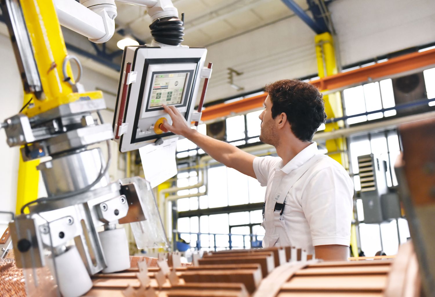 Young mechanical engineering workers operate a machine for winding copper wire - manufacture of transformaers in a factory. Transformer Manufacturing